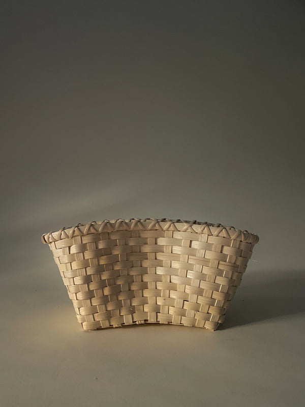 A handwoven natural rattan crescent clutch with a simple, elegant design displayed against a neutral background.