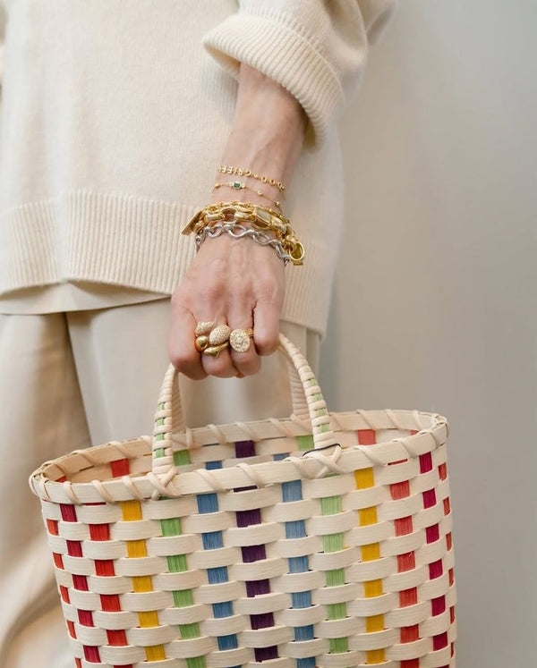 Person holding a colorful woven basket with a neutral background