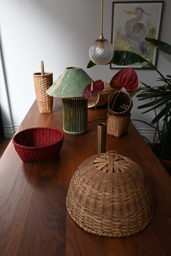 Decorative items on a wooden table including a wicker basket, ceramic lamp, and plants.