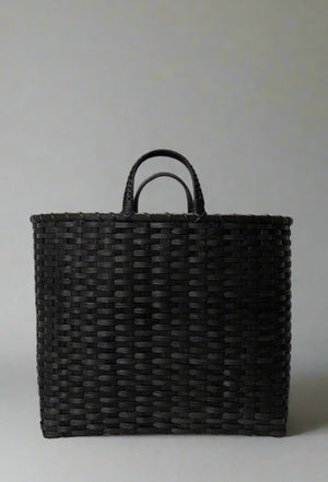 Black woven basket with handles on a light gray background