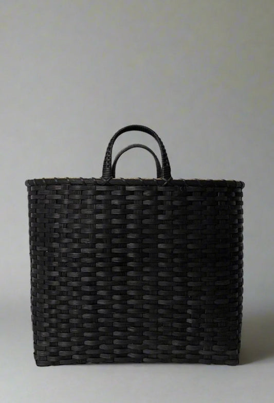 Black woven basket with handles on a light gray background