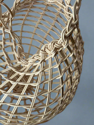 Close-up of a woven beige spherical object against a neutral background