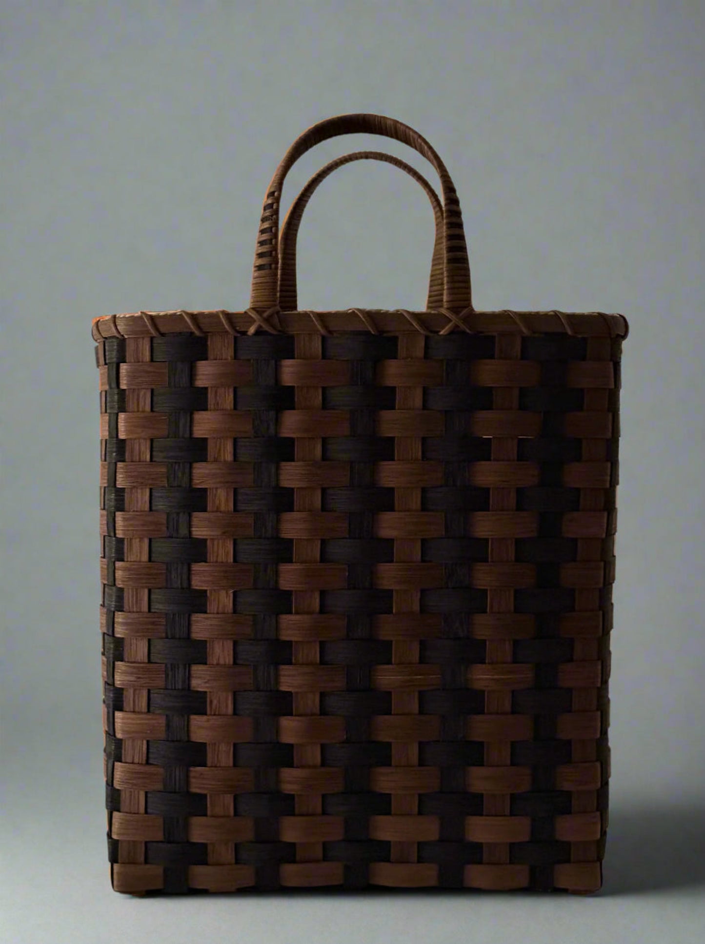 Woven brown bag with handles on a light gray background