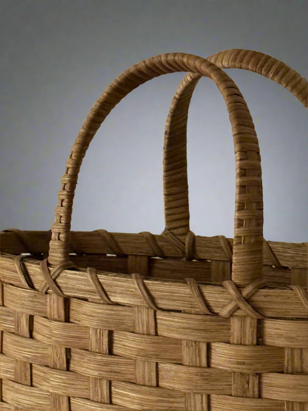 Close-up of a woven basket with a handle on a plain background