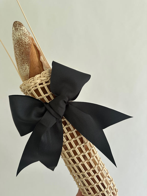 Decorative item with woven design and black bow on a neutral background