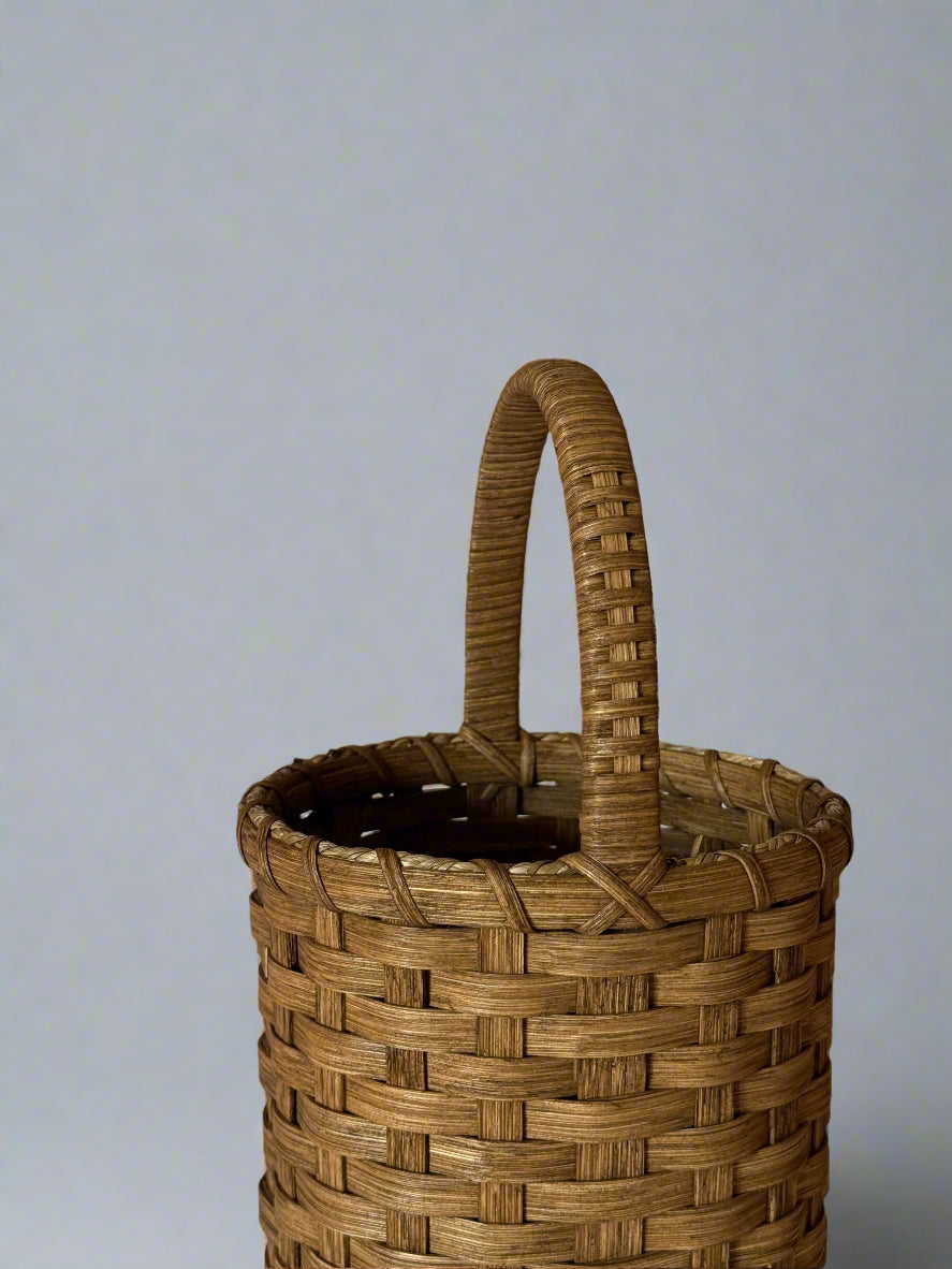 Woven basket with a handle on a plain background