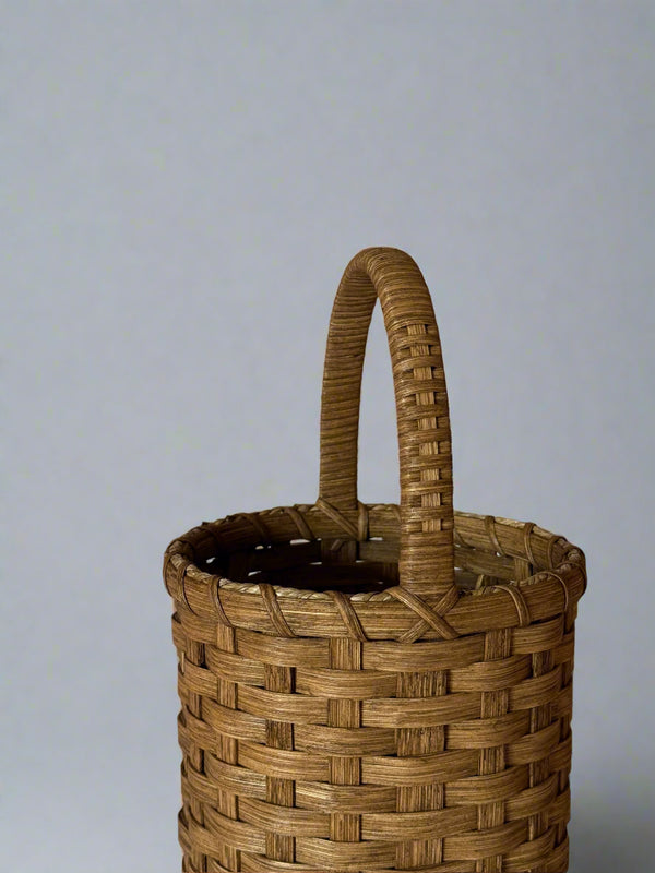 Woven basket with a handle on a plain background