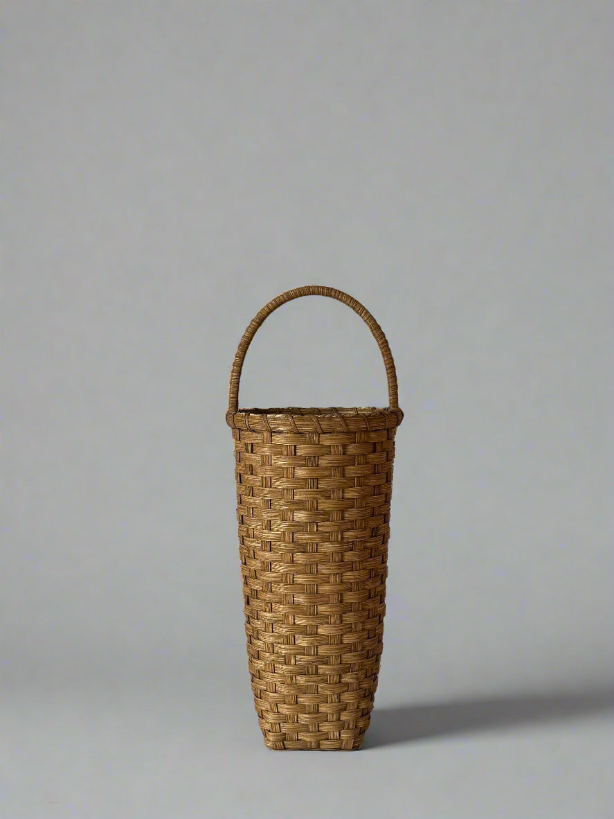 Woven basket with a handle on a plain background