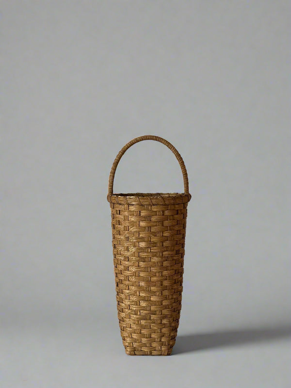 Woven basket with a handle on a plain background