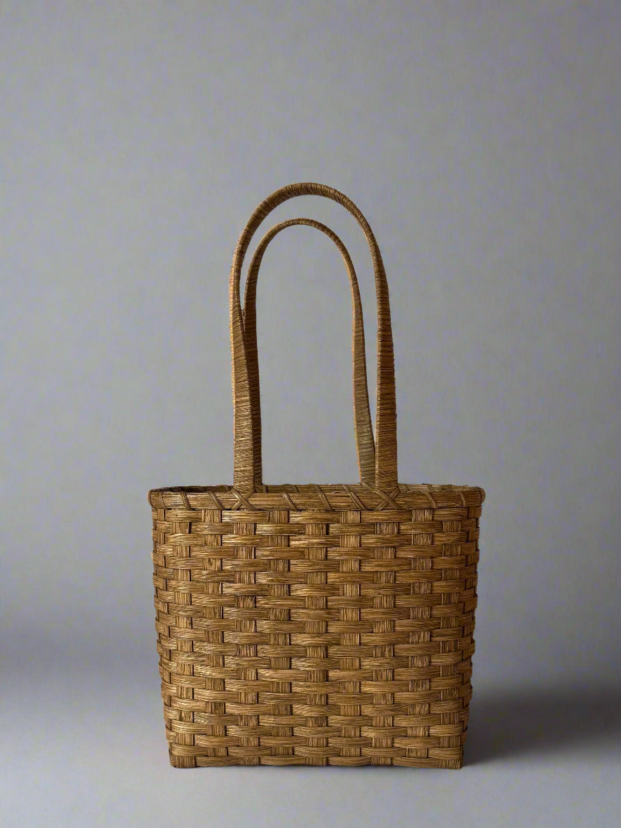 Woven brown basket with handles on a white background
