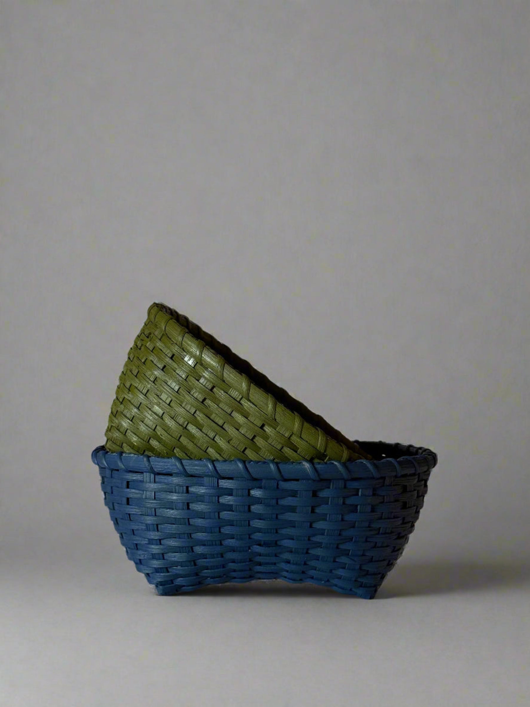 Two woven baskets, one green and one blue, on a light background