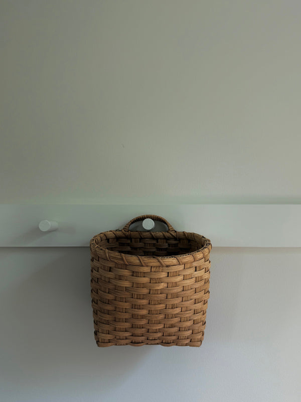 Woven basket on a white shelf against a plain wall