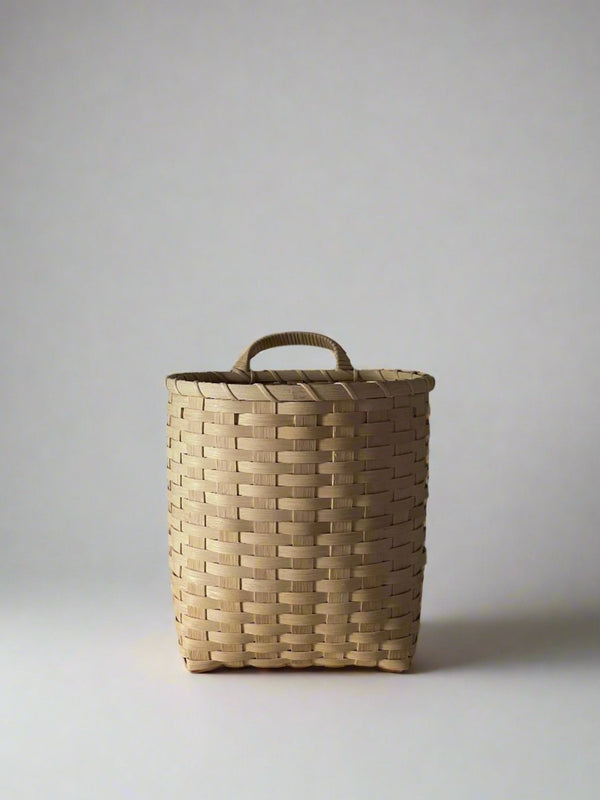 Woven basket with a handle on a plain background