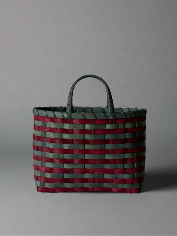 Woven basket with red and green pattern on a gray background