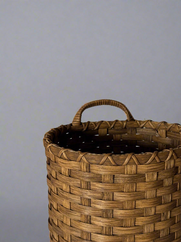 Woven basket with a handle on a light gray background