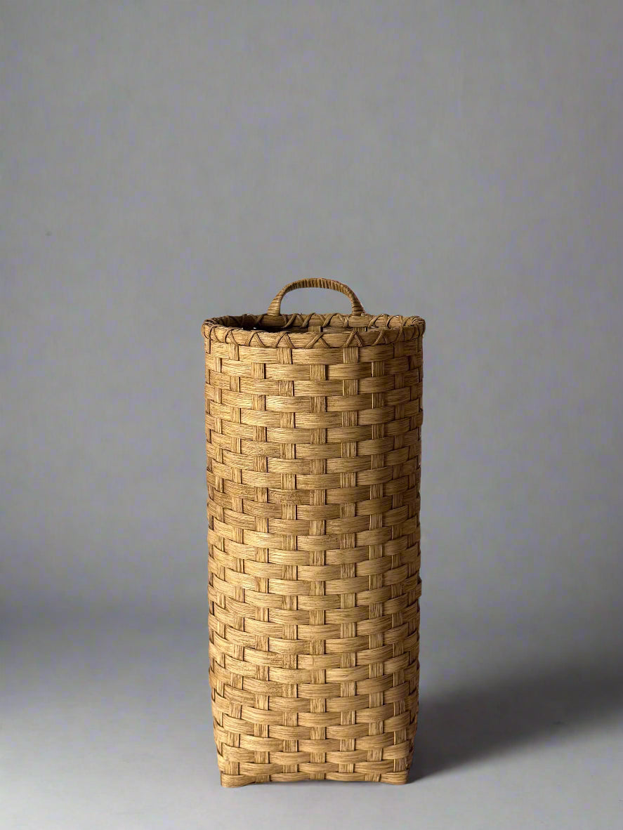 Woven basket with a handle on a plain background