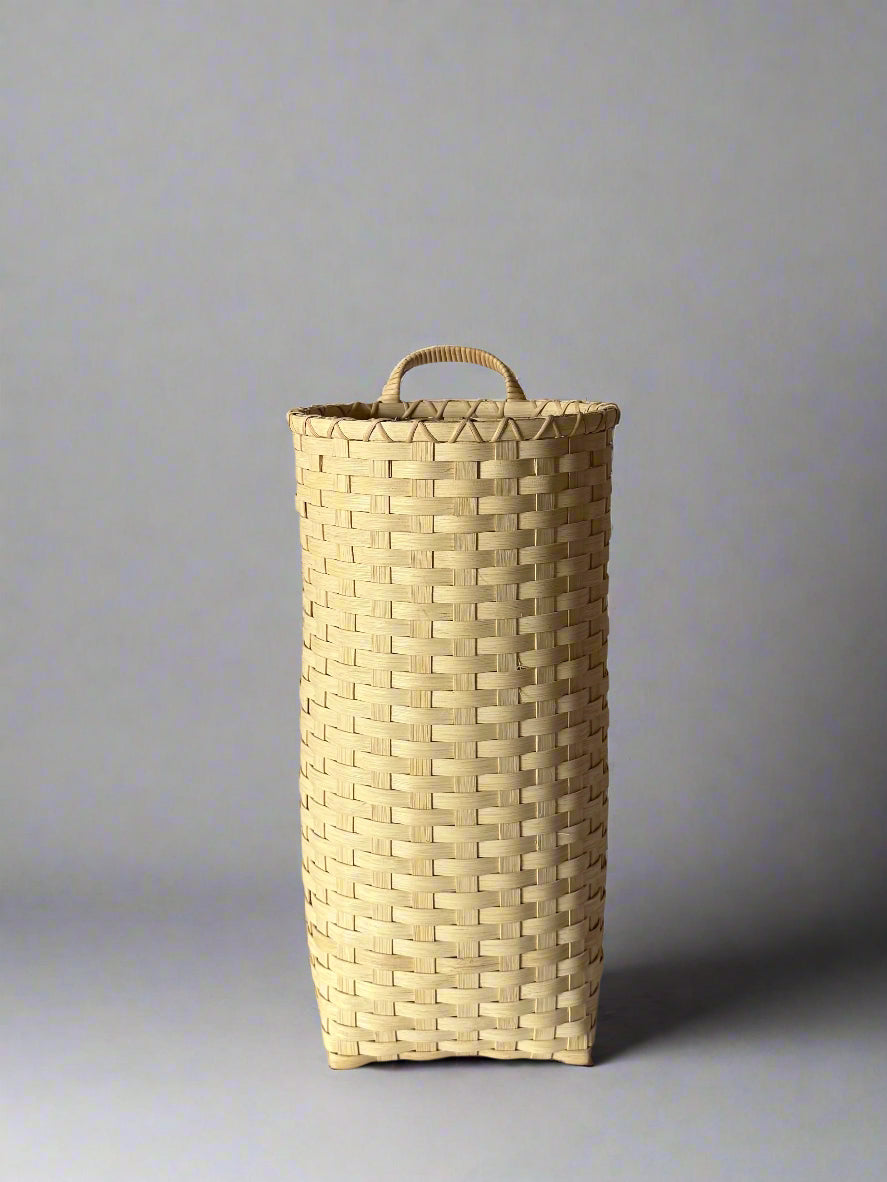 Woven basket with a handle on a plain background