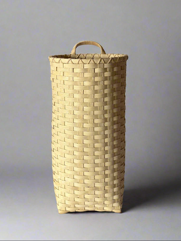 Woven basket with a handle on a plain background