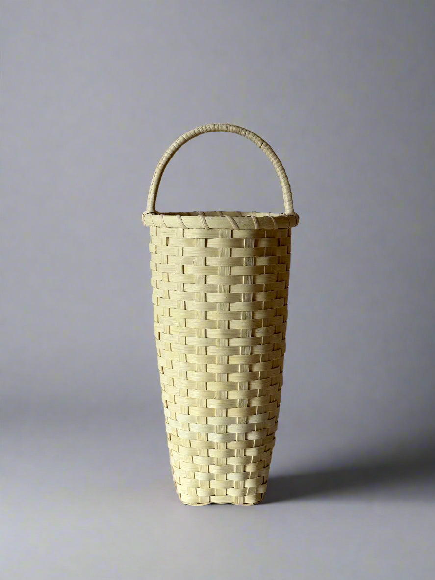 Woven basket with a handle on a gray background