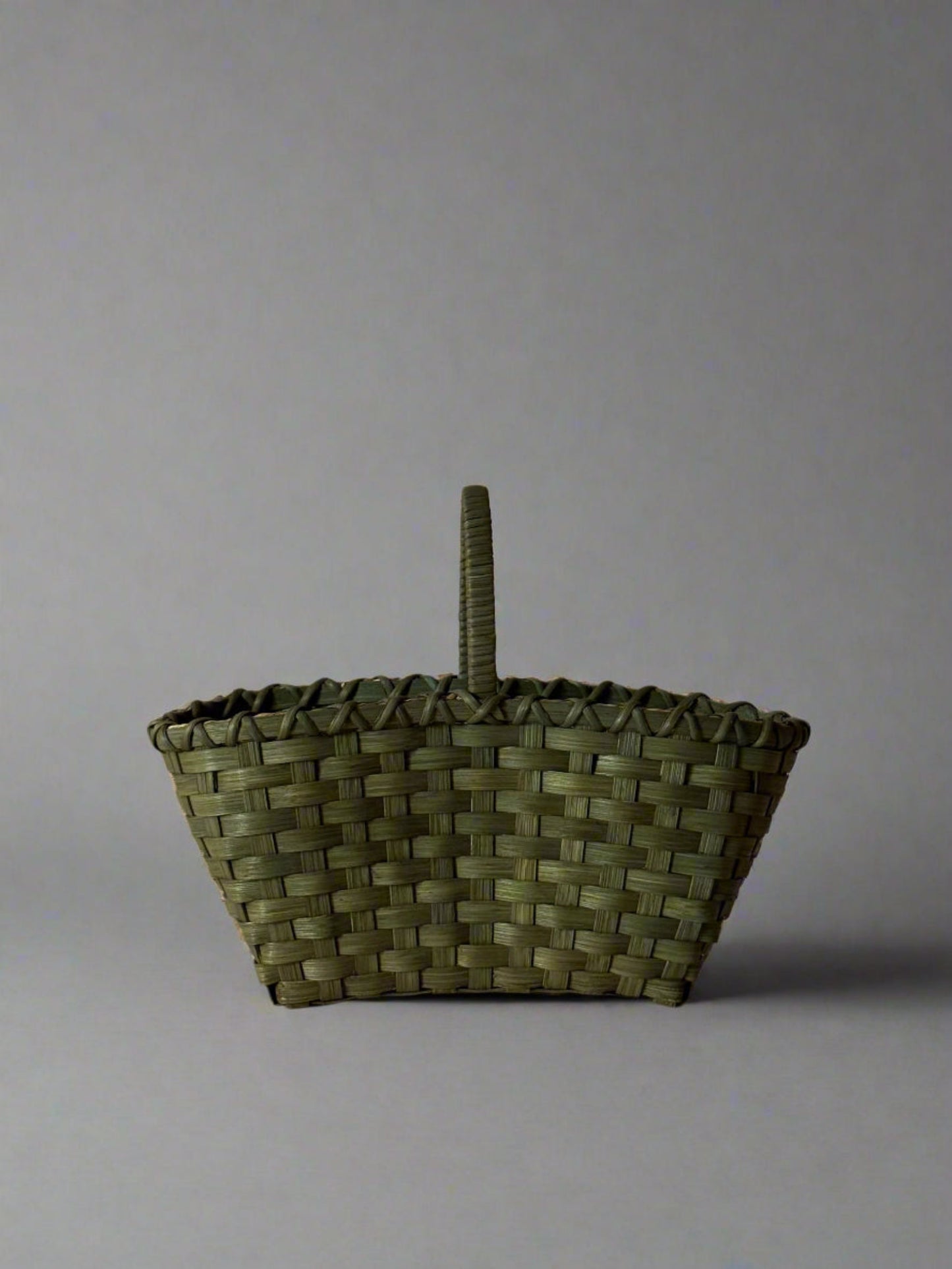 Woven basket with a handle on a plain background