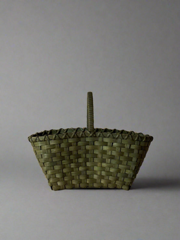 Woven basket with a handle on a plain background