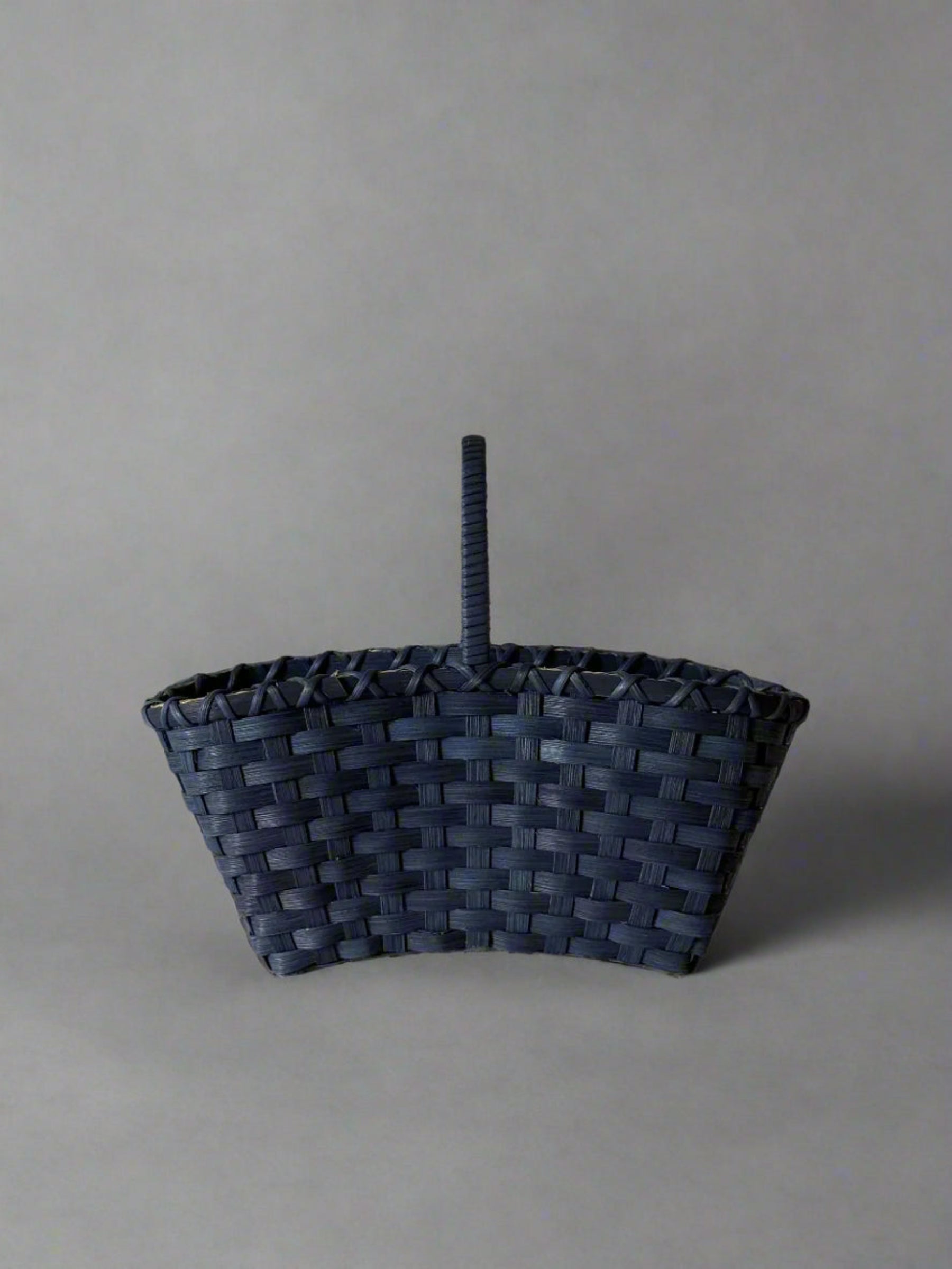 Woven basket with a handle on a light gray background