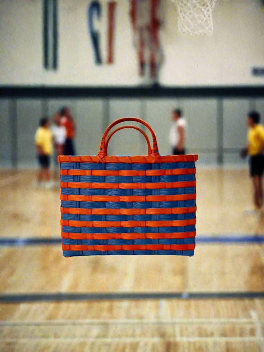 Blue and orange woven bag floating over a body of water with a cloudy sky.