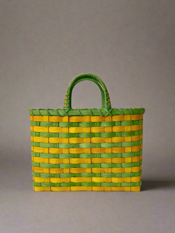 Woven basket with green top and yellow sides on a gray background