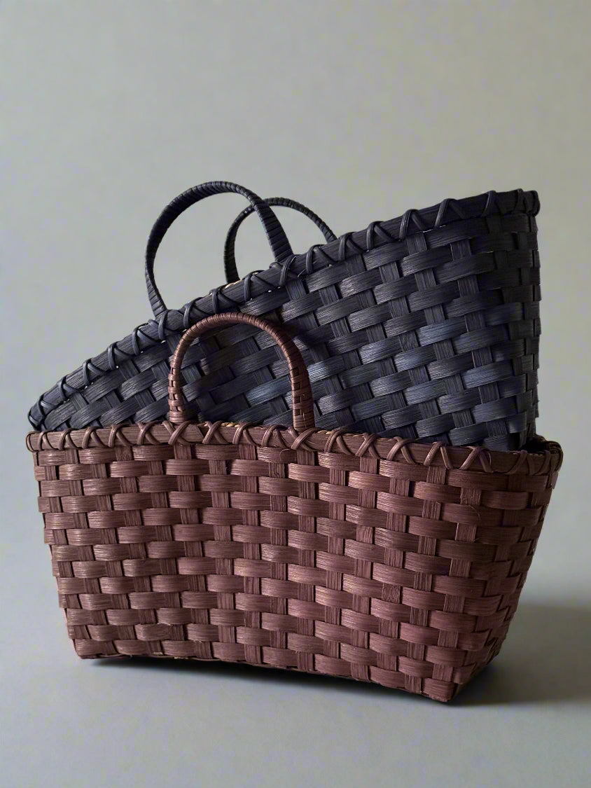 Two woven baskets, one brown and one black, on a light gray background.