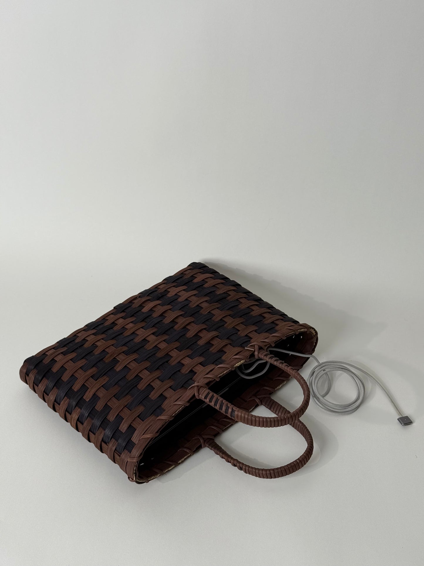 Woven brown and black bag on a white background