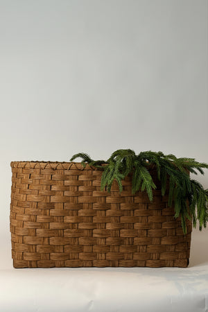 Woven basket with greenery against a plain background