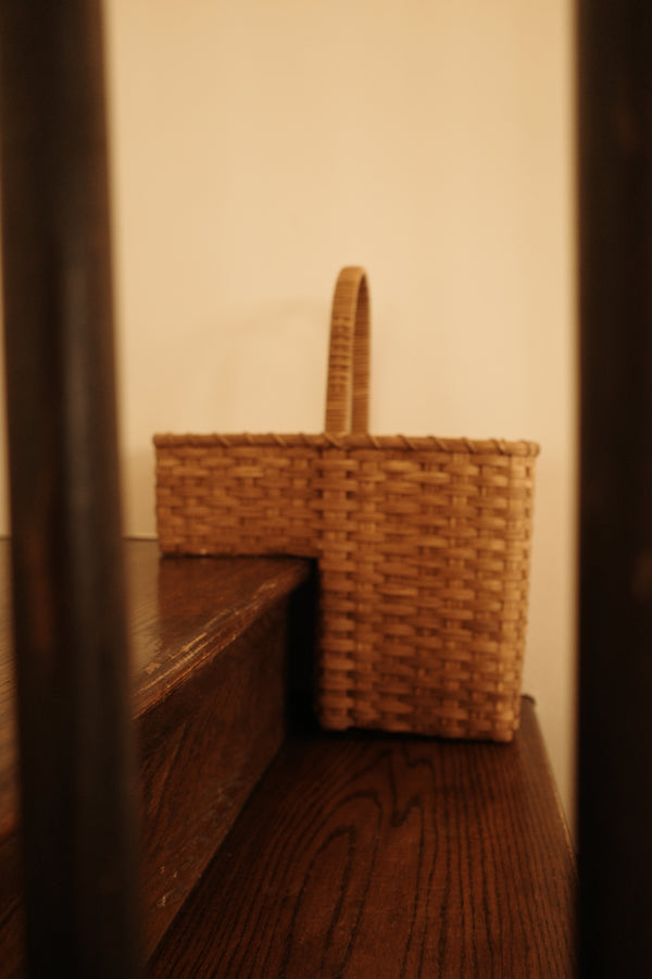 A stair tote basket with a single loop handle.