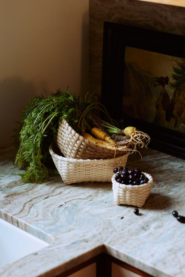 Wicker baskets with vegetables and fruits on a stone countertop